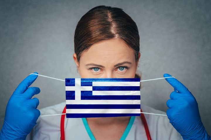 Coronavirus in Greece Female Doctor Portrait hold protect Face surgical medical mask with Greece National Flag. Illness, Virus Covid-19 in Greece, concept photo