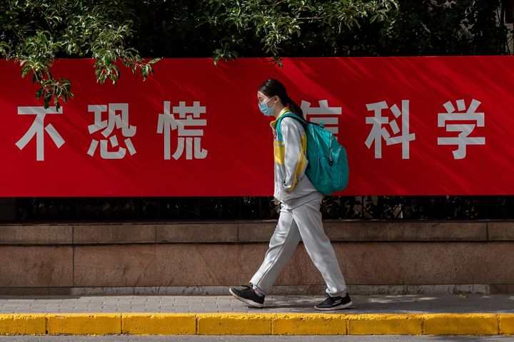 "Όχι πανικός. Εμπιστευτείτε την επιστήμη" γράφει πανό μπροστά από την οποία περνά μια μαθήτρια σήμερα στο Πεκίνο. 