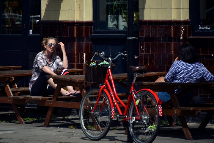 Two women sit outside a closed pub on Saturday as Britain faces its seventh week of lockdown