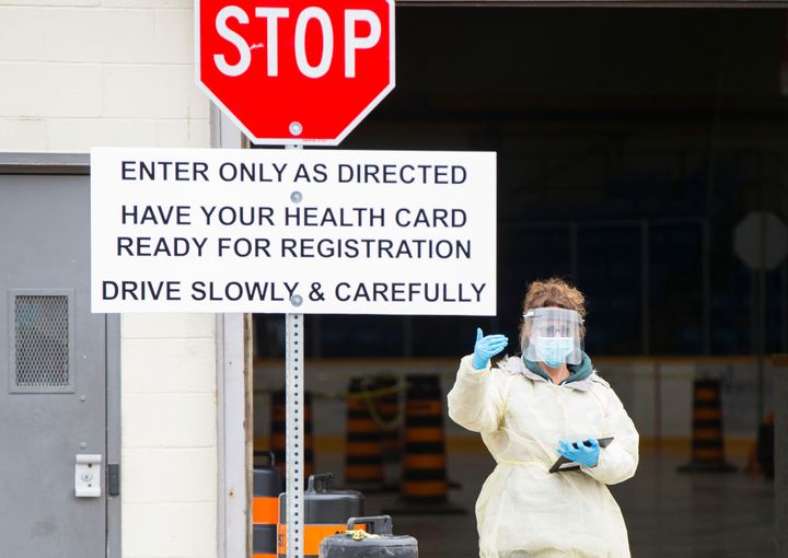 A medical worker directs a vehicle at a drive-thru COVID-19 testing centre in Hamilton, Ont., on April 23, 2020.