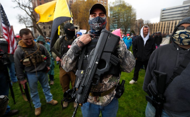 A protester carries his rifle at the state Capitol in Lansing, Michigan, on April 30, 2020. Hoisting U.S. flags and handmade signs, protesters denounced Gov. Gretchen Whitmer's stay-at-home order and business restrictions amid the pandemic.