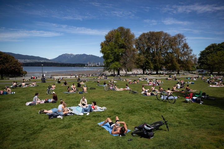 People sit and lie in the sun at Kitsilano Beach Park as temperatures reached high into the 20s in Vancouver on May 9, 2020.