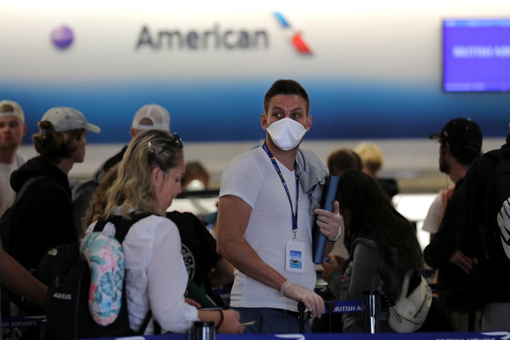 A passenger wearing a mask waits in line to check in for a flight at Miami International Airport in Miami, Florida, on March