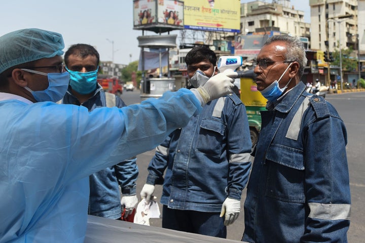 A health worker checks the body temperature of a Ahmedabad Fire & Emergency Services official during a nationwide lockdown as a preventive measure against the COVID-19 coronavirus in the Walled City region of Ahmedabad on April 8, 2020.