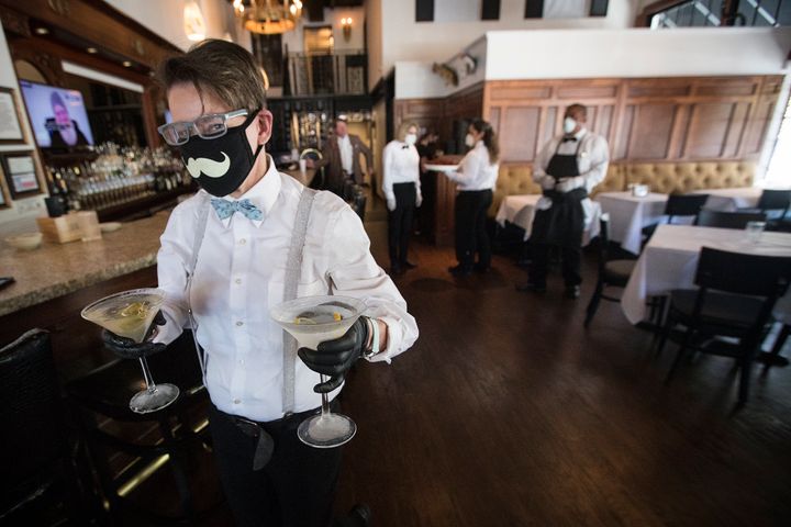 Σερβιτόρα κρατάει ποτά για να τα προσφέρει στους πελάτες σε εστιατόριο στο Χιούστον του Τέξας. Ολοι οι εργαζόμενοι φορούν προστατευτικές μάσκες και γάντια. 