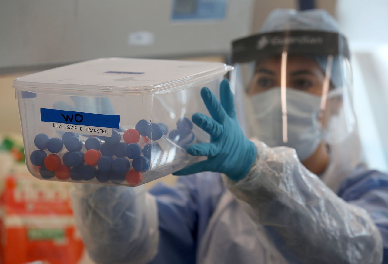 A laboratory technician holding test tubes containing live samples taken from people tested for the novel coronavirus at a laboratory in Glasgow