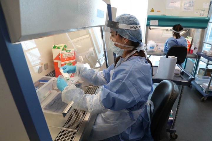 Laboratory technicians unpack boxes with test tubes containing live coronavirus samples at a new Lighthouse laboratory in Glasgow