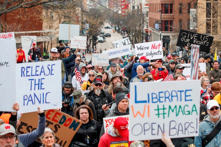 People hold signs during a protest against the coronavirus shutdown in front of the state Capitol in Madison, Wisconsin, on April 24.