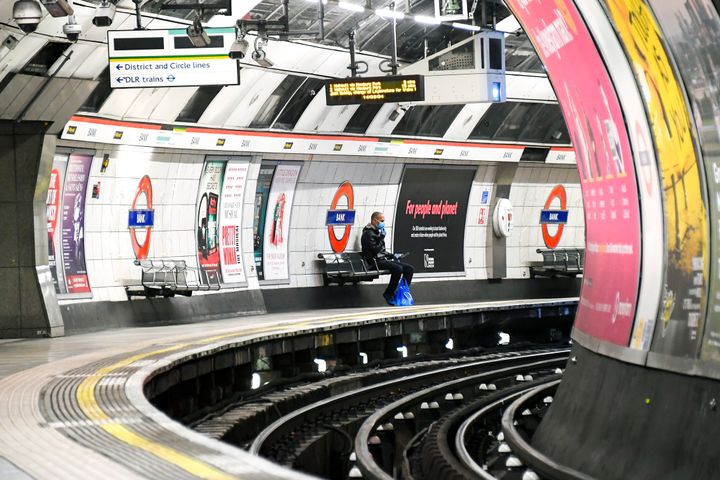 A man wearing a protective face mask to protect against coronavirus, waits for a Central Line underground train on an empty platform at Bank Station in London.