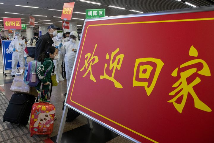 Passengers from Wuhan walk past a sign that reads "Welcome Home" as they arrive on a high speed train in Beijing after lockdown lifted in April.