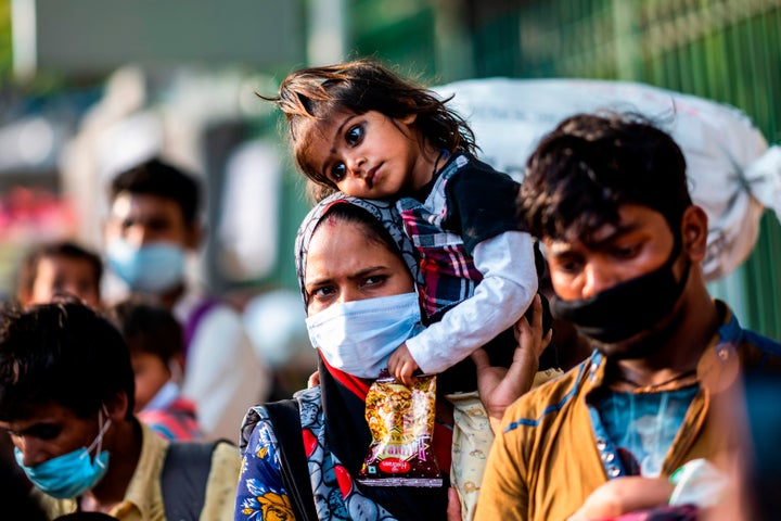 A migrant worker carries her daughter on her shoulder as she walks along a street in New Delhi on May 13, 2020.