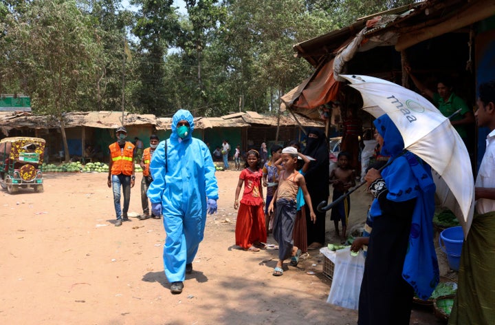 In this April 15, 2020, photograph, a health worker from an aid organization walks wearing a hazmat suit at the Kutupalong Ro