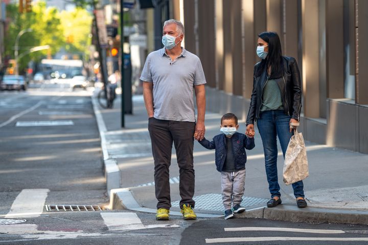 A family wearing masks waits to cross the street amid the coronavirus pandemic on May 14 in New York City