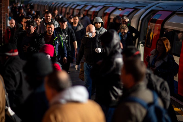 Commuters exit the tube at West Ham station in East London on May 14, 2020.