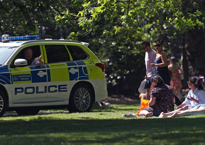 Police officers in a patrol car move sunbathers on in Greenwich Park, as the UK continues its lockdown to help curb the spread of coronavirus, in London, Saturday May 9, 2020. (Yui Mok/PA via AP)