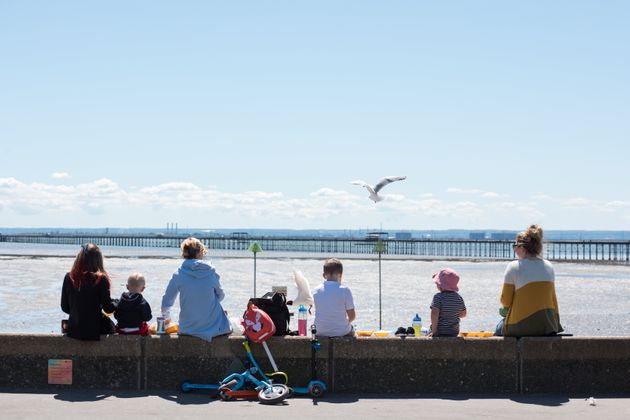 SOUTHEND ON SEA, ENGLAND - MAY 15: People with children sit on the seawall eating chips as various food...