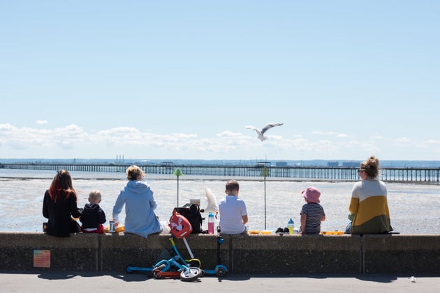 SOUTHEND ON SEA, ENGLAND - MAY 15: People with children sit on the seawall eating chips as various food...