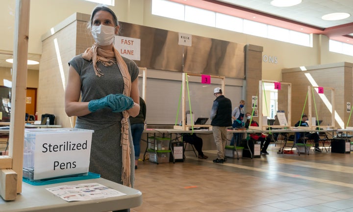 \Poll worker Rhonda Griffin stands ready to hand out sterilized pens at a polling place on April 7, 2020 in Sun Prairie, Wisc.