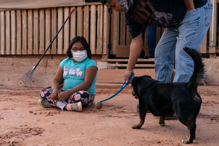 Annabelle Dinehdeal, 8, watches as her father Eugene Dinehdeal, plays ball with their dog Wally on their family compound in Tuba City, Arizona, on the Navajo reservation. The family has been devastated by COVID-19. The Navajo reservation has some of the highest rates of coronavirus in the country.