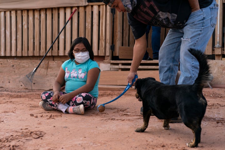 Annabelle Dinehdeal, 8, watches as her father Eugene Dinehdeal, plays ball with their dog Wally on their family compound in Tuba City, Arizona, on the Navajo reservation. The family has been devastated by COVID-19. The Navajo reservation has some of the highest rates of coronavirus in the country.