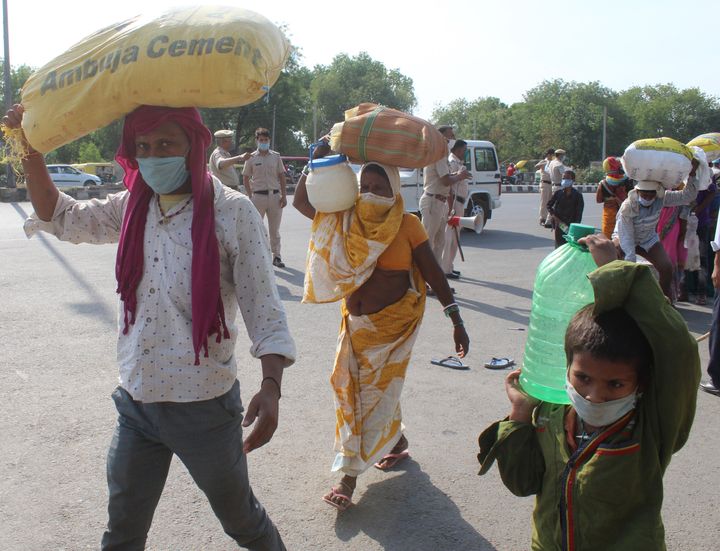  Stranded migrant workers head to a temporary shelter home inside Tau Devi Lal Stadium after Gurugram Police dispersed their gathering on the road amid lockdown, on May 15, 2020 in Gurugram