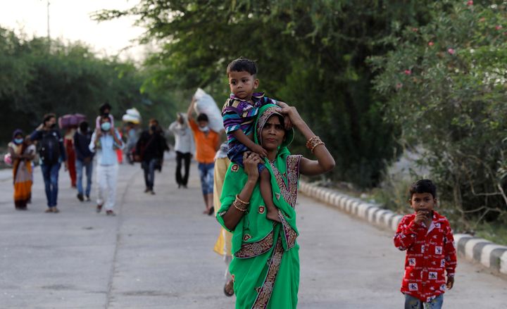 A migrant worker carries her child, as they make their way across the border to their home state of Uttar Pradesh, during an extended nationwide lockdown to slow the spread of the coronavirus disease (COVID-19), in New Delhi, India, May 15