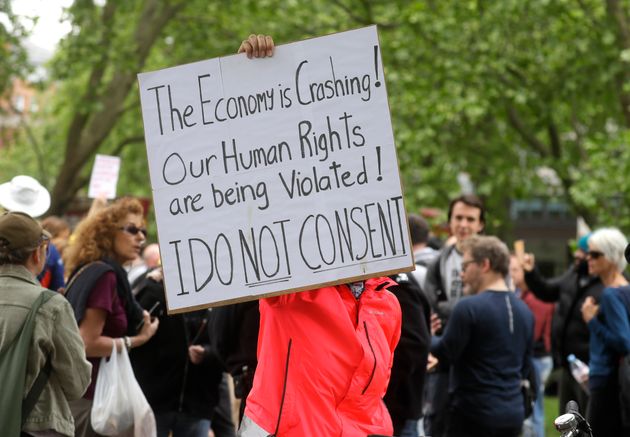 A protestor holds up a banner during a mass gathering protest in Hyde Park. 