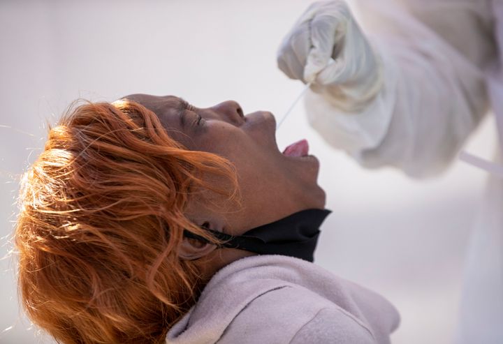 Μια γυναίκα ανοίγει το στόμα της για να συλλεχθεί δείγμα για το τεστ του Covid-19