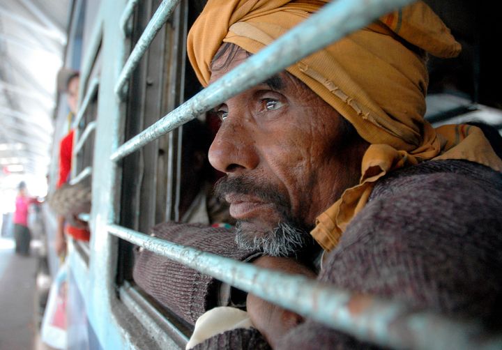 A migrant labourer looks out of a window as he waits in a train compartment in Guwahati, the major city of India's northeastern state of Assam January 9, 2007. Huddled in buses, trucks and trains, thousands of poor migrant labourers fled revolt-torn Assam on Tuesday, the second day of an exodus triggered by the killing of scores of workers by separatists. REUTERS/Utpal Baruah (INDIA)