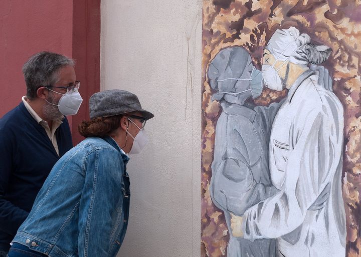 スペイン・マラガ（5月15日）。マスクをつけた看護師がキスする姿を描いた絵を見る、マスクをつけた人たち。
