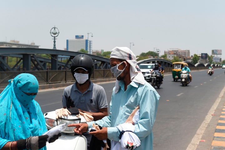 A vendor sells facemasks and hand gloves to commuters along a road in Ahmedabad on May 16, 2020.