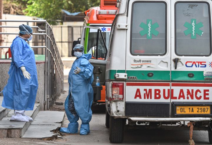 An ambulance driver (R) in PPE coveralls interacts with a medial worker outside the Covid-19 ward, at Lok Nayak Jai Prakash Narayan Hospital (LNJP), on May 15, 2020 in New Delhi.