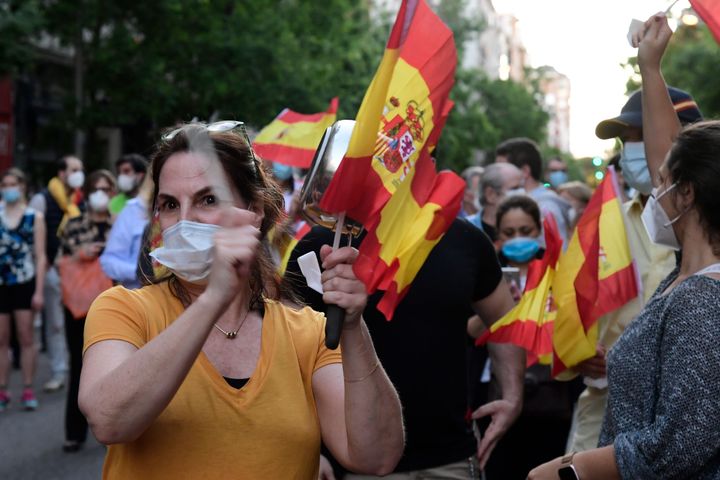 A woman bangs a pot during a protest against the government for its coronavirus crisis management in front of the ruling Socialist Party headquarters in Madrid on May 18, 2020.
