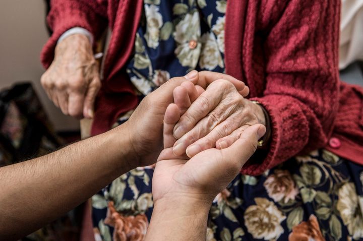 Nurse holding hands with elderly patient.