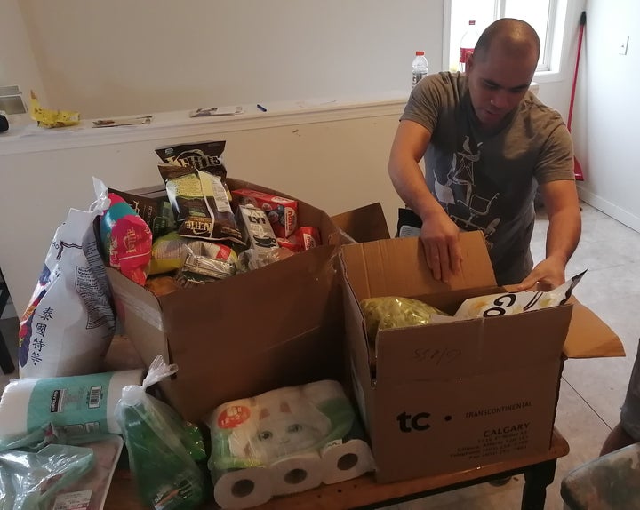 One of Miranda's roommates unpacks toilet paper and food donations, arranged by grassroots group Migrante Alberta.