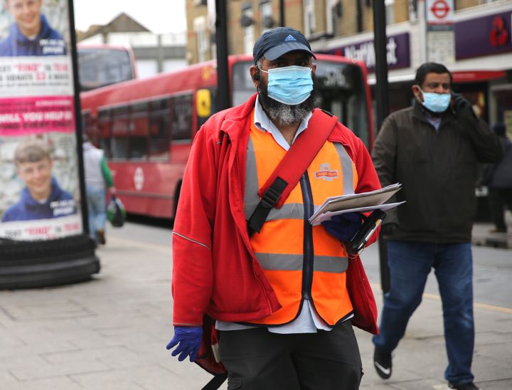A postman wearing protective personal equipment walks through East Ham, east London.