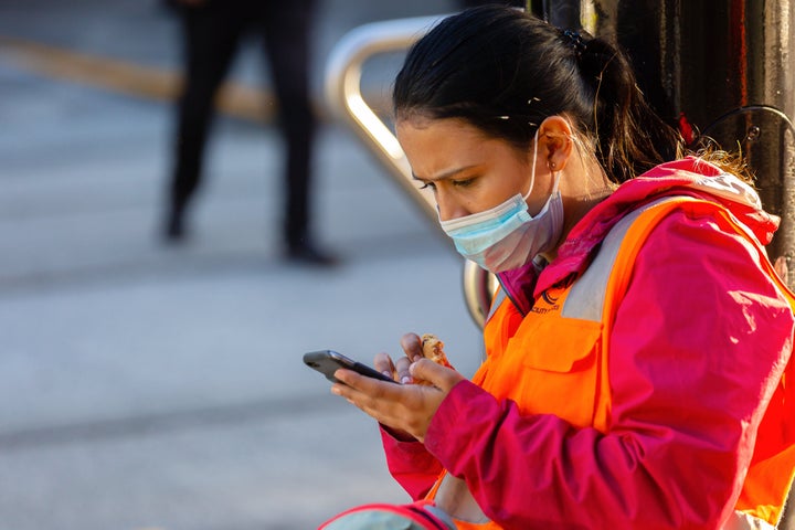 A woman wearing a face mask uses her phone during the coronavirus pandemic on May 16 in Melbourne, Australia. (Photo by Speed