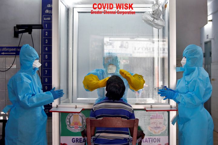 A doctor in a protective chamber takes a swab from a man to test for coronavirus disease (COVID-19) at a Walk-In Sample Kiosk (WISK) in a government-run hospital in Chennai, April 13, 2020.