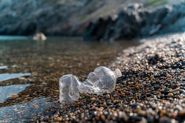 Empty plastic bottle lying on stony beach at seaside