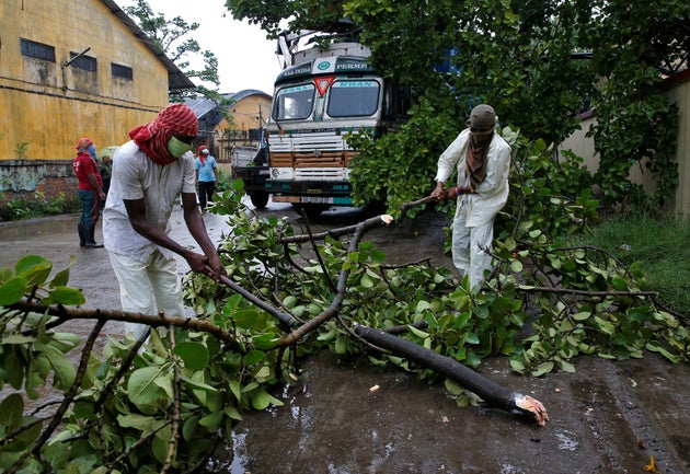 Rescue workers cut tree branches that fell on a truck trailer after heavy winds caused by Cyclone Amphan,...