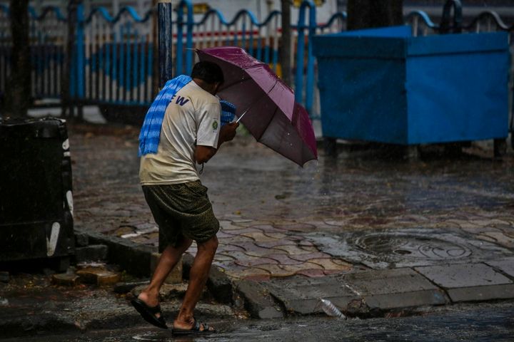 A man struggles to hold his umbrella and walk against high wind in Kolkata, Wednesday, May 20, 2020. 