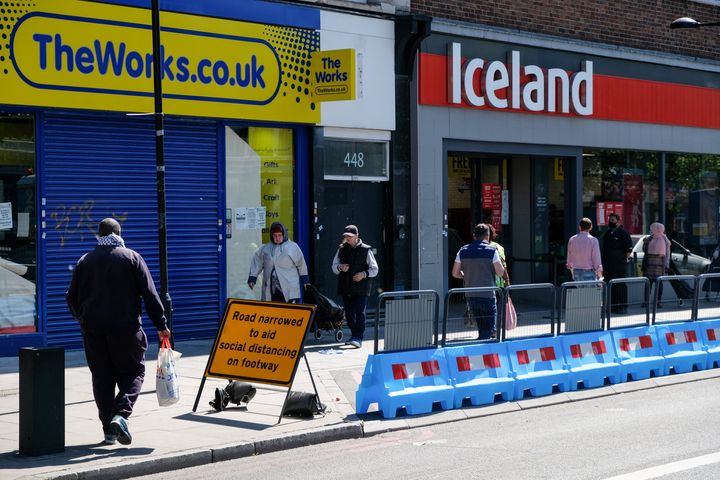 A road in north London is narrowed to aid social distancing while shoppers queue for a supermarket