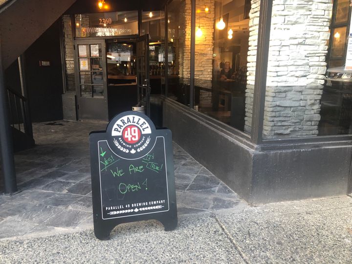 A sign outside St. Augustine's pub in East Vancouver reads "yes, it's true! We are open!" 