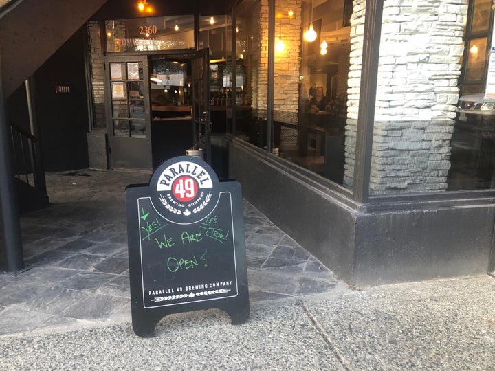 A sign outside St. Augustine's pub in East Vancouver reads "yes, it's true! We are open!"
