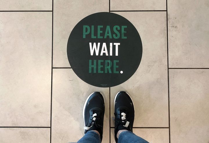 A social distancing measure sticker on the floor inside a Starbucks.