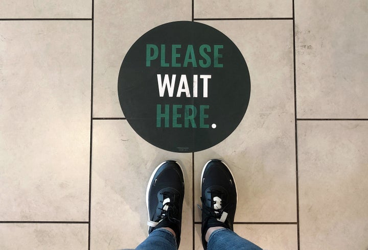 A social distancing measure sticker on the floor inside a Starbucks.