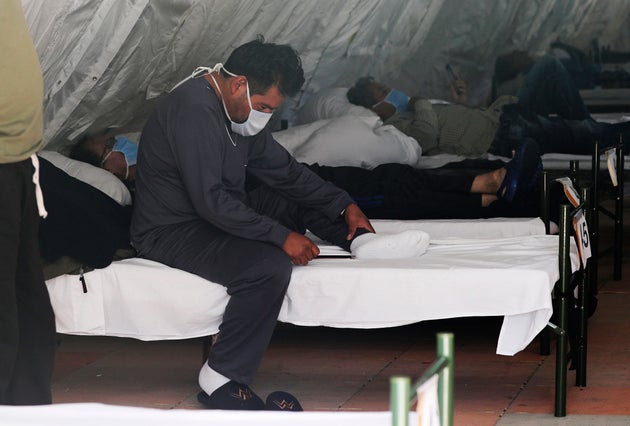 Men diagnosed with COVID-19 who do not have severe symptoms rest inside a tent designated for male patients, set up outside the