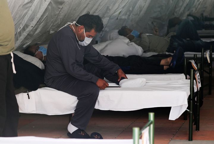 Men diagnosed with COVID-19 who do not have severe symptoms rest inside a tent designated for male patients, set up outside the "Instituto de Seguridad Social Sur" hospital in Quito, Ecuador, Wednesday, May 20, 2020. (AP Photo/Dolores Ochoa)