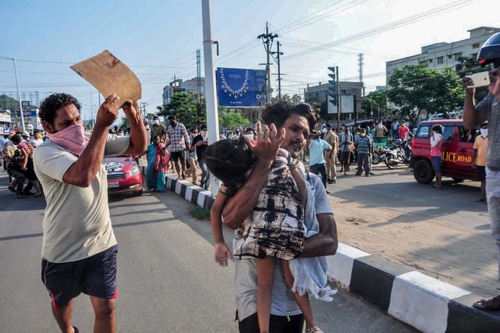 A man carries a fainted young girl (R) to evacuate her following a gas leak incident at an LG Polymers plant in Visakhapatnam on May 7, 2020. 
