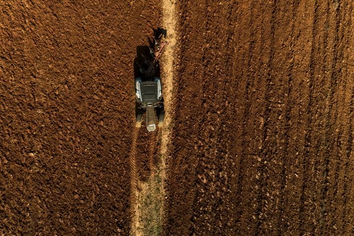 Aerial drone shot of a farmer in tractor seeding, sowing agricultural crops at field in the fertile farm fields of Kilkis in North Greece